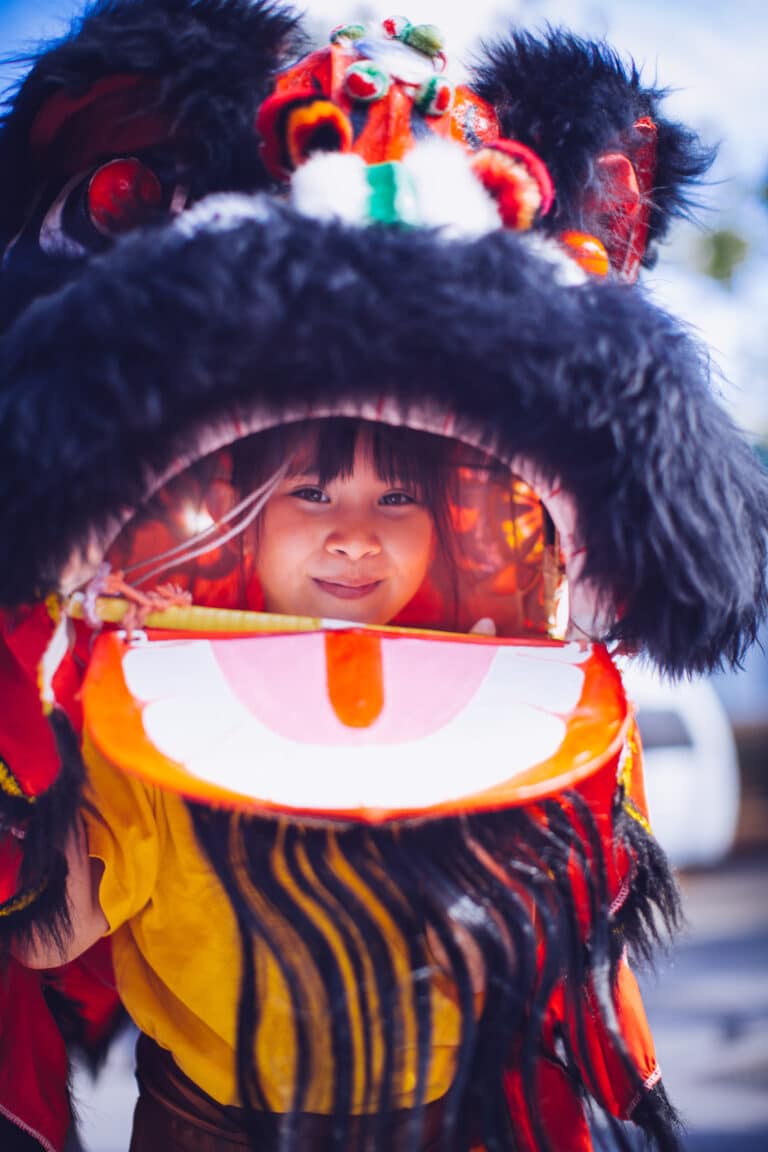 Asian girl inside dragon costume, looking out of the mouth