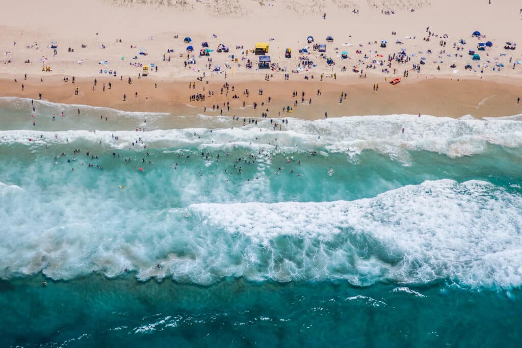 aerial view of people on beach as waves roll in