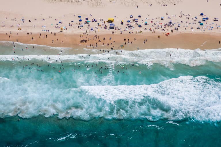 aerial view of people on beach as waves roll in