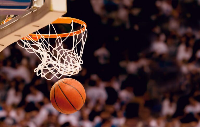 Basketball going through hoop with blurred out fans in the background