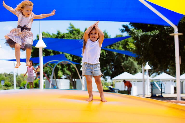 Two girls jumping on yellow bouncing pillow