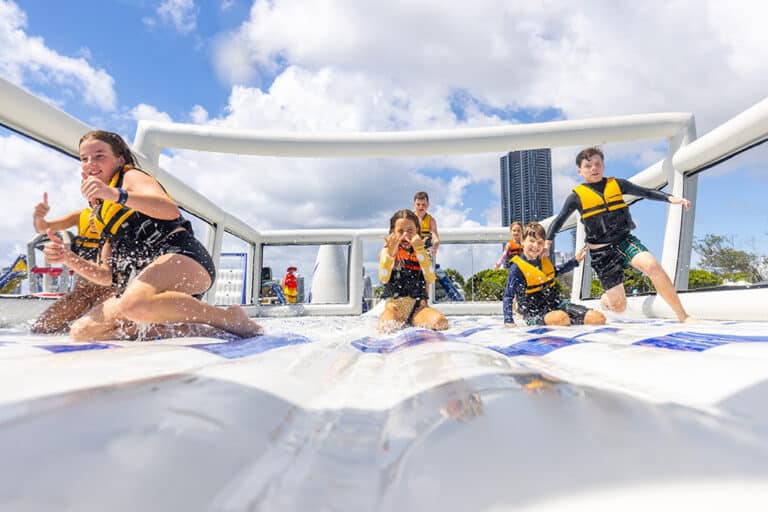 Children with yellow life-jackets on, sliding on a water park inflatable slide
